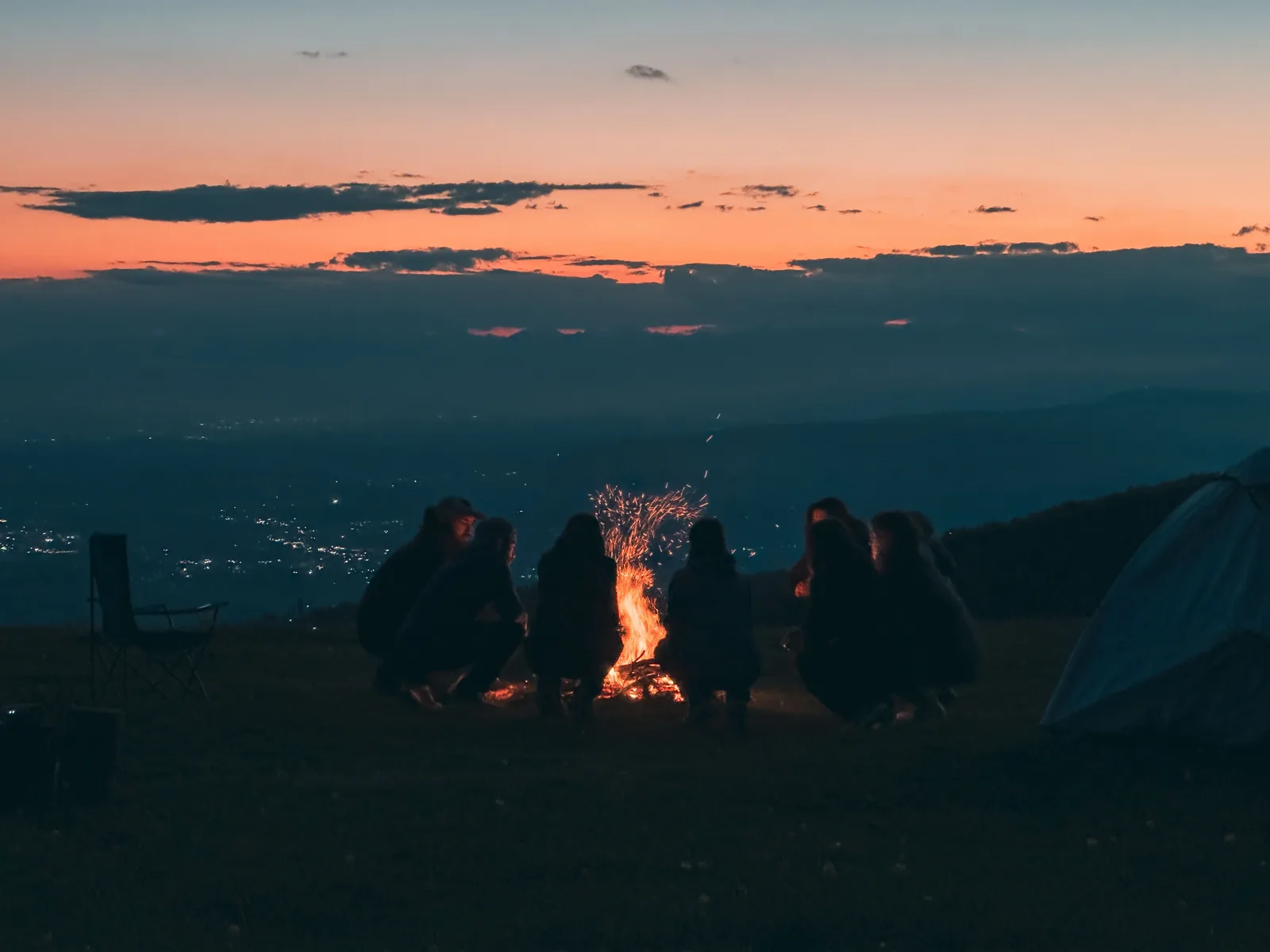 Travellers gathered around a campfire under the evening sky